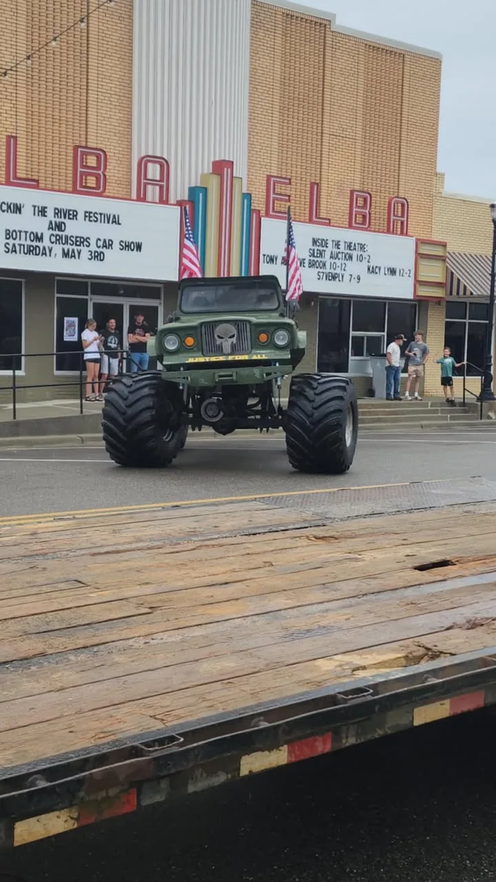 Sarge the Megatruck driving past the Elba theatre marquee with American flags flying