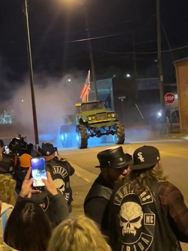 Sarge doing a burnout at night with smoke and an American flag, crowd filming on phones